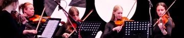 Žákyně hrají na housle v orchestru