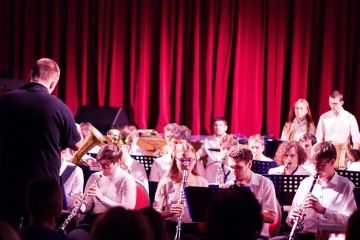 Dechový orchestr žáků hraje pod vedením dirigenta