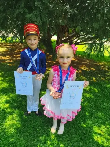 Dvě malé tanečnice v kostýmech s diplomy a medailemi