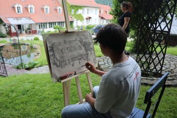 Žák kreslí budovu na stojanu v zahradě