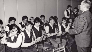 Archivní fotografie žáků hrajících na dechové nástroje s pedagogem