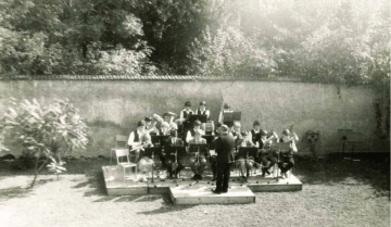 Archivní fotografie orchestru hrajícího venku na pódiu